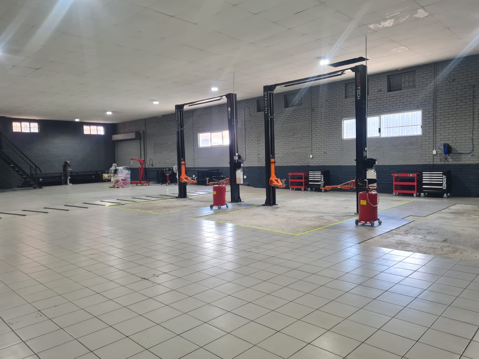 Spacious industrial garage with three car lifts and tiled flooring